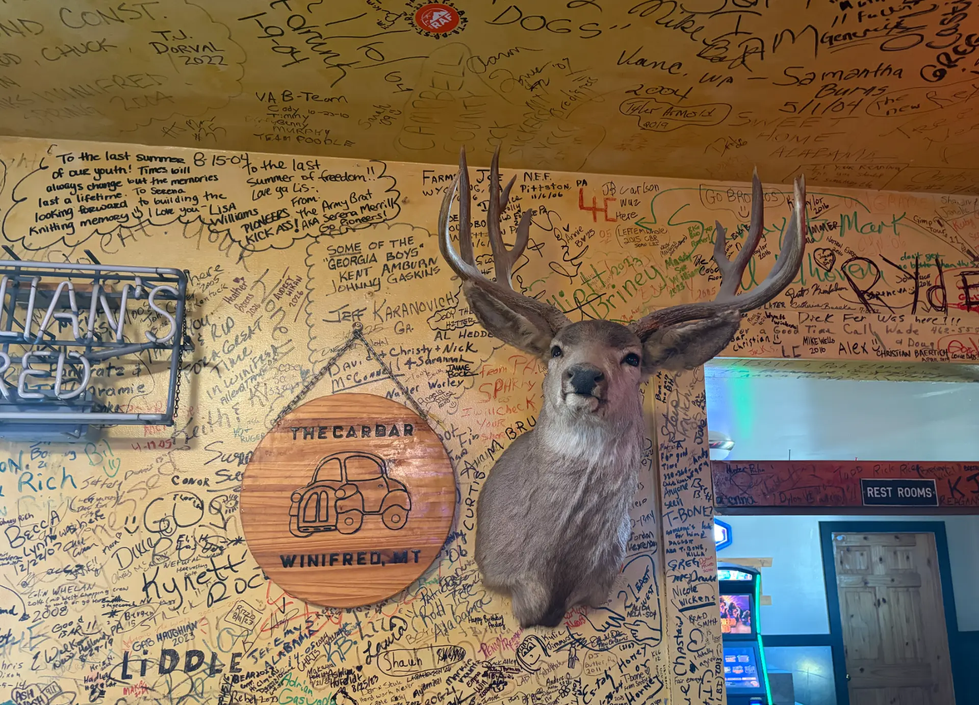 Walls covered in visitor signatures with a deer mount at the Carr Bar