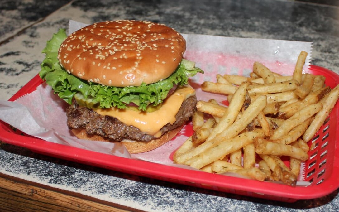 The famous Winifred Tavern cheeseburger with melted cheese and a side of seasoned fries